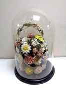 A Victorian glass dome on stand containing ceramic flowers,