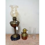 An antique German brass oil lamp with glass shade on cast iron base together with a further brass