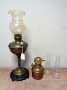 An antique German brass oil lamp with glass shade on cast iron base together with a further brass