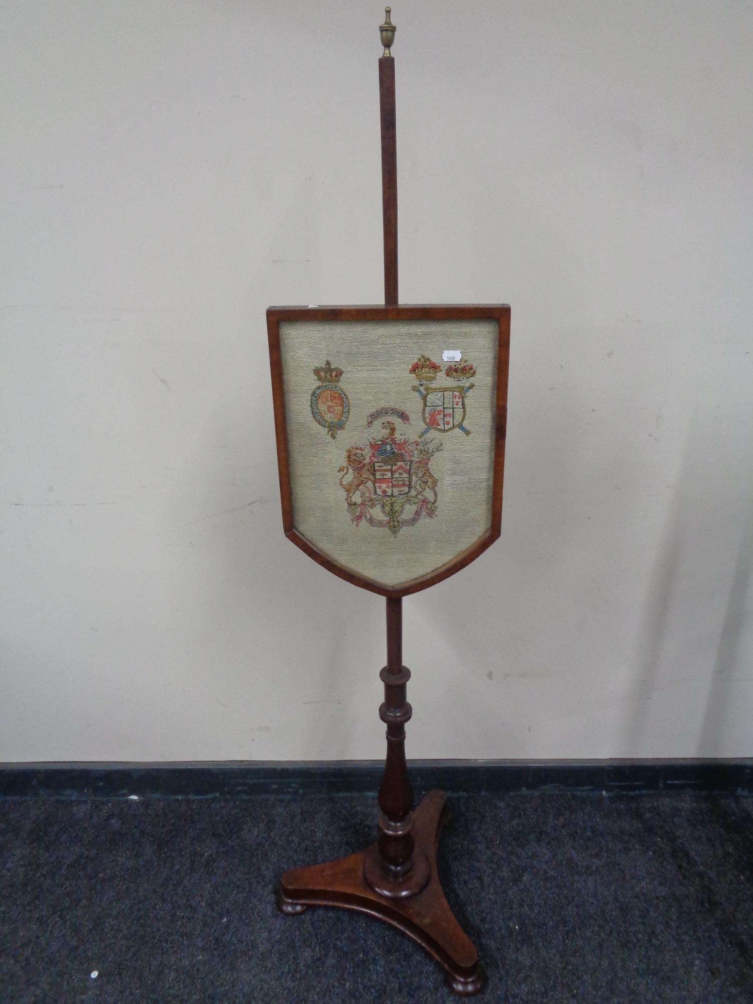 A Victorian mahogany pole screen with embroidered armorial panel