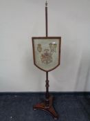 A Victorian mahogany pole screen with embroidered armorial panel