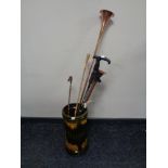 A glazed ceramic stick stand containing copper and brass hunting horns, riding crop,