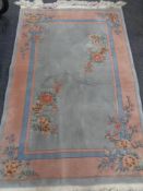 A Chinese fringed floral embossed rug on blue and pink ground,