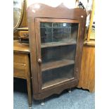 A glazed door corner cabinet on raised legs