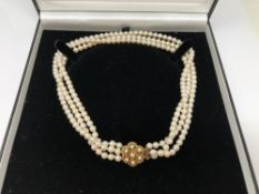 A triple strand cultured pearl necklace with gold clasp,