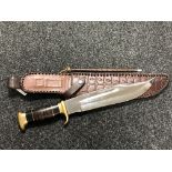 A heavy quality bowie knife with brass mounted grip and stitched leather sheath with sharpener