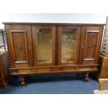 A continental style oak four door sideboard with two carved panel doors,