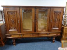 A continental style oak four door sideboard with two carved panel doors,