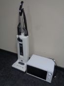 A Sebo automatic upright vacuum together with a microwave