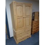 A stripped pine double door wardrobe fitted four drawers beneath,