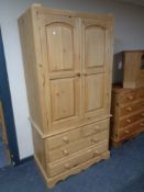 A stripped pine double door wardrobe fitted four drawers beneath,