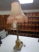 A brass Corinthian column table lamp with pink tasseled shade
