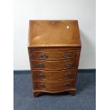 An inlaid yew wood serpentine fronted lady's bureau fitted four drawers beneath