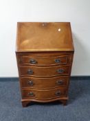 An inlaid yew wood serpentine fronted lady's bureau fitted four drawers beneath