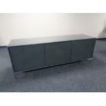 A contemporary triple door low sideboard with plate glass top,