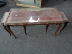 A nest of three glass topped tables with red leather inset panels