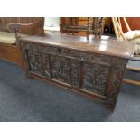 A George III panelled oak coffer with later carving