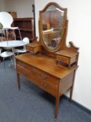 A late Victorian inlaid mahogany three drawer dressing table on raised legs with shield mirror