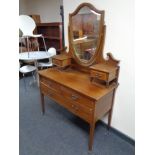 A late Victorian inlaid mahogany three drawer dressing table on raised legs with shield mirror