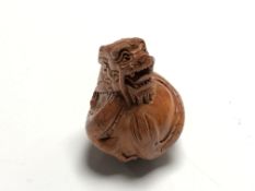 A carved Chinese hardwood netsuke - Dragon holding an egg