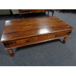 A contemporary sheesham wood four drawer coffee table on raised legs