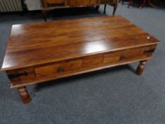 A contemporary sheesham wood four drawer coffee table on raised legs