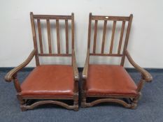 A pair of oak rail back low armchairs with studded leather seats