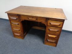 A 1930s oak twin pedestal writing desk fitted nine drawers