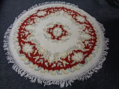 Two Chinese fringed circular rugs on cream ground