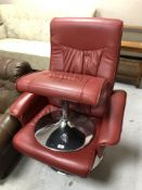 A red leather upholstered swivel chair on chrome base with matching footstool