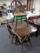 An Ercol stained elm drop leaf rectangular dining table together with a set of four spindle back