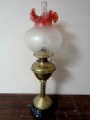 A brass oil lamp with two tone etched glass shade