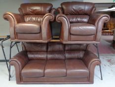 A brown leather three piece lounge suite comprising of three seater settee and pair of armchairs