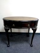 A continental carved oval occasional table on claw and ball feet with leather inset top