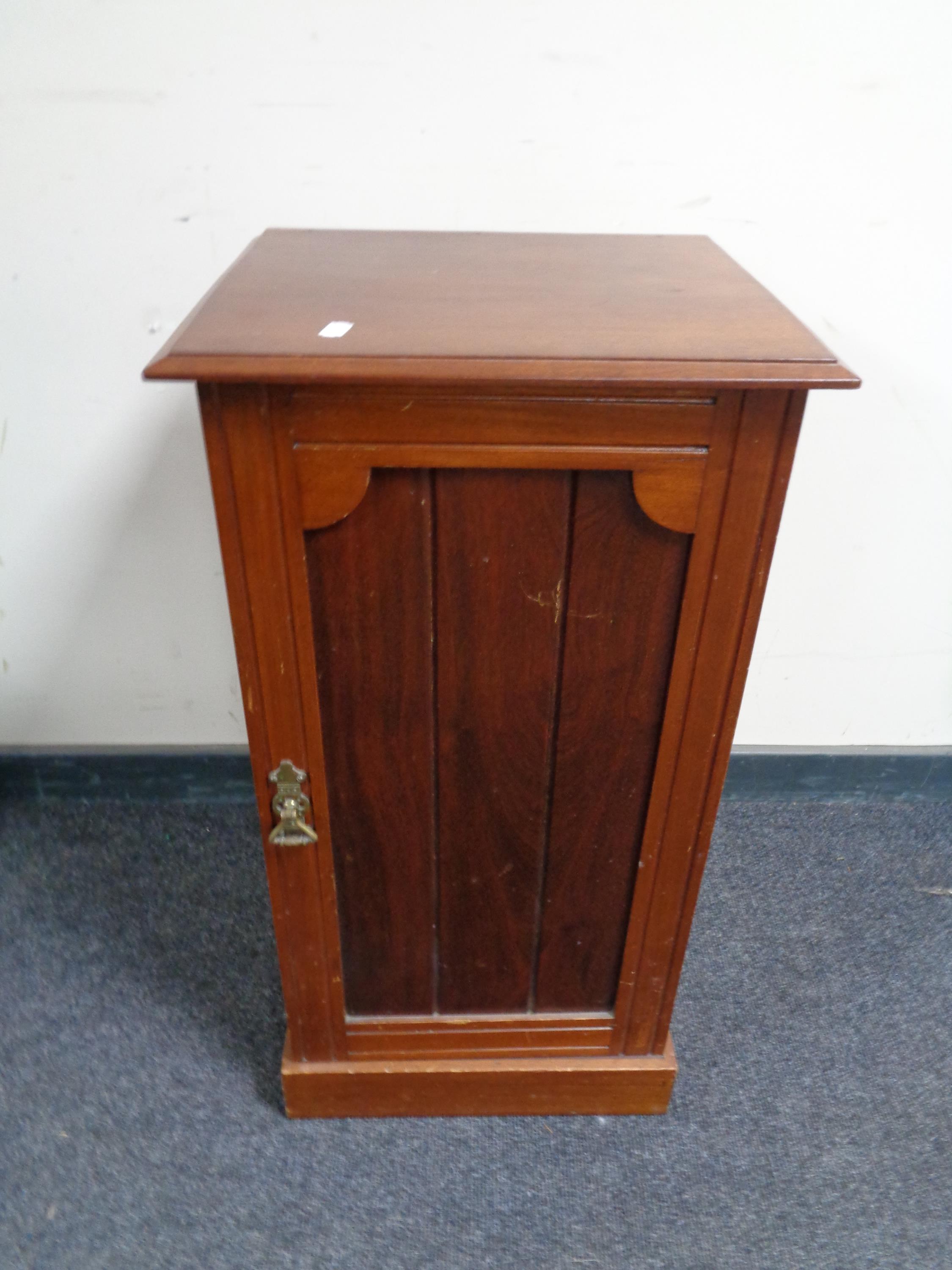 A mahogany single door cabinet together with a small painted stool and a wicker and metal three