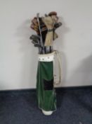 A leather golf bag containing vintage drivers and other clubs