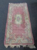 A Chinese fringed rug on pink ground