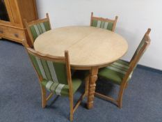 A circular blonde oak dining table together with a set of four chairs in green striped upholstery