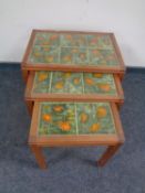 A nest of three teak tables with tile inset tops