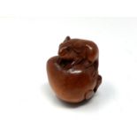 A carved Chinese hardwood netsuke - Rat seated on a peach