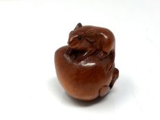 A carved Chinese hardwood netsuke - Rat seated on a peach