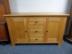 A contemporary oak sideboard fitted two cupboard doors around three central drawers