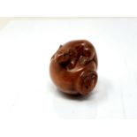 A carved Chinese hardwood netsuke - Rat climbing on a pot