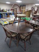 An Ercol stained elm drop leaf dining table together with a set of four spindle back armchairs