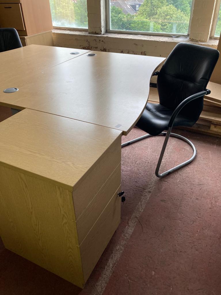 A light oak effect desk, width 140 cm, together with taller three chest and black leather chair.