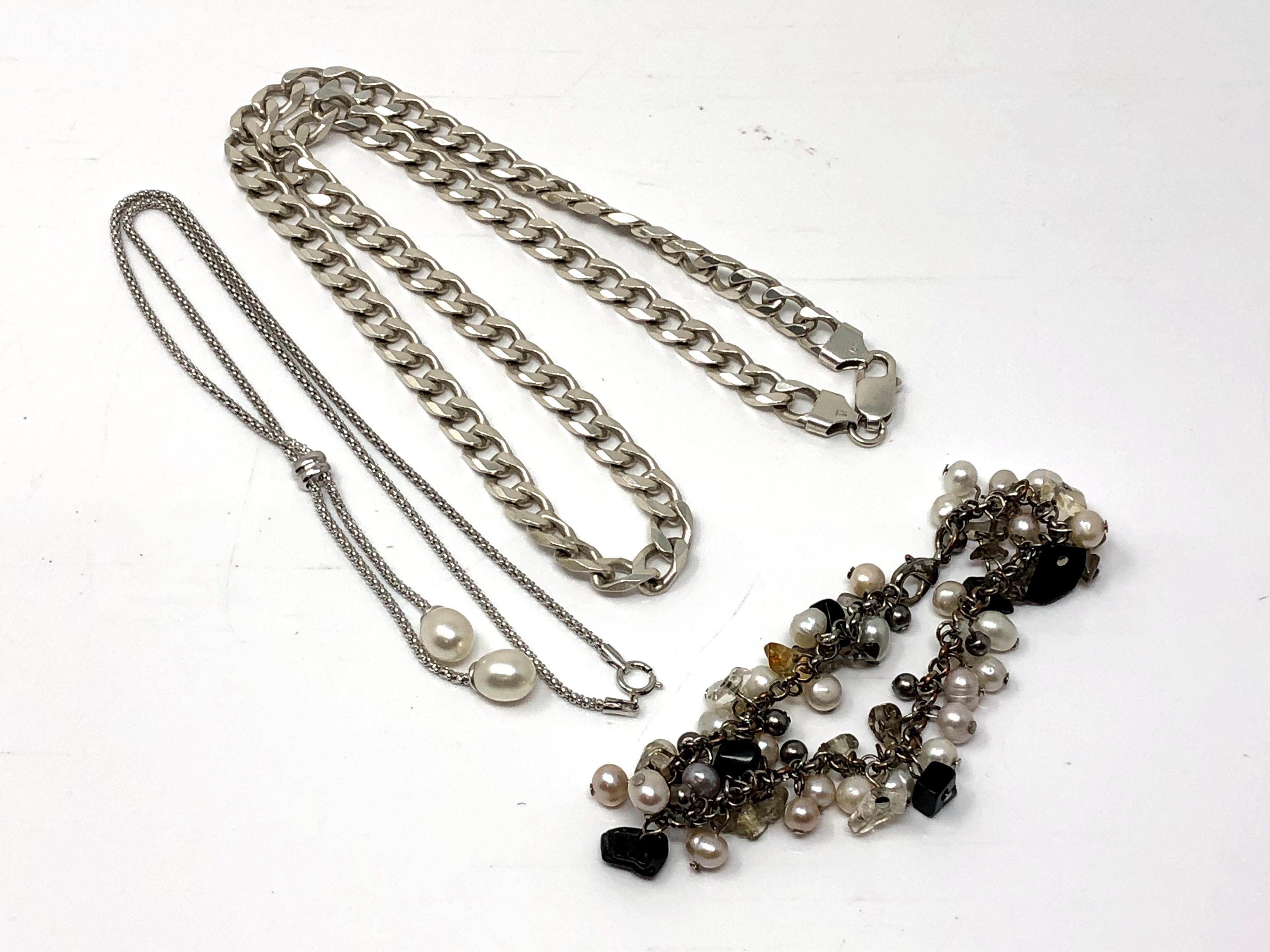 A silver curb link necklace, an unusual pearl bracelet and a pearl necklace.