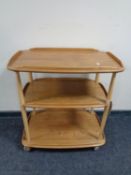 An Ercol elm and beech three tier tea trolley on castors