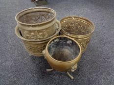 Three embossed brass planters together with a further brass planter on raised feet