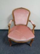 A carved beech salon armchair upholstered in a pink dralon