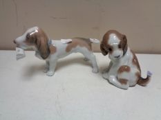 Two Lladro figures of a hound with butterfly on tail and hound with newspaper.